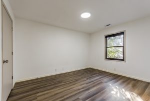 A third bedroom with plank floors, bright white walls and a window