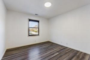 Bedroom with plank floors, bright white walls and a window